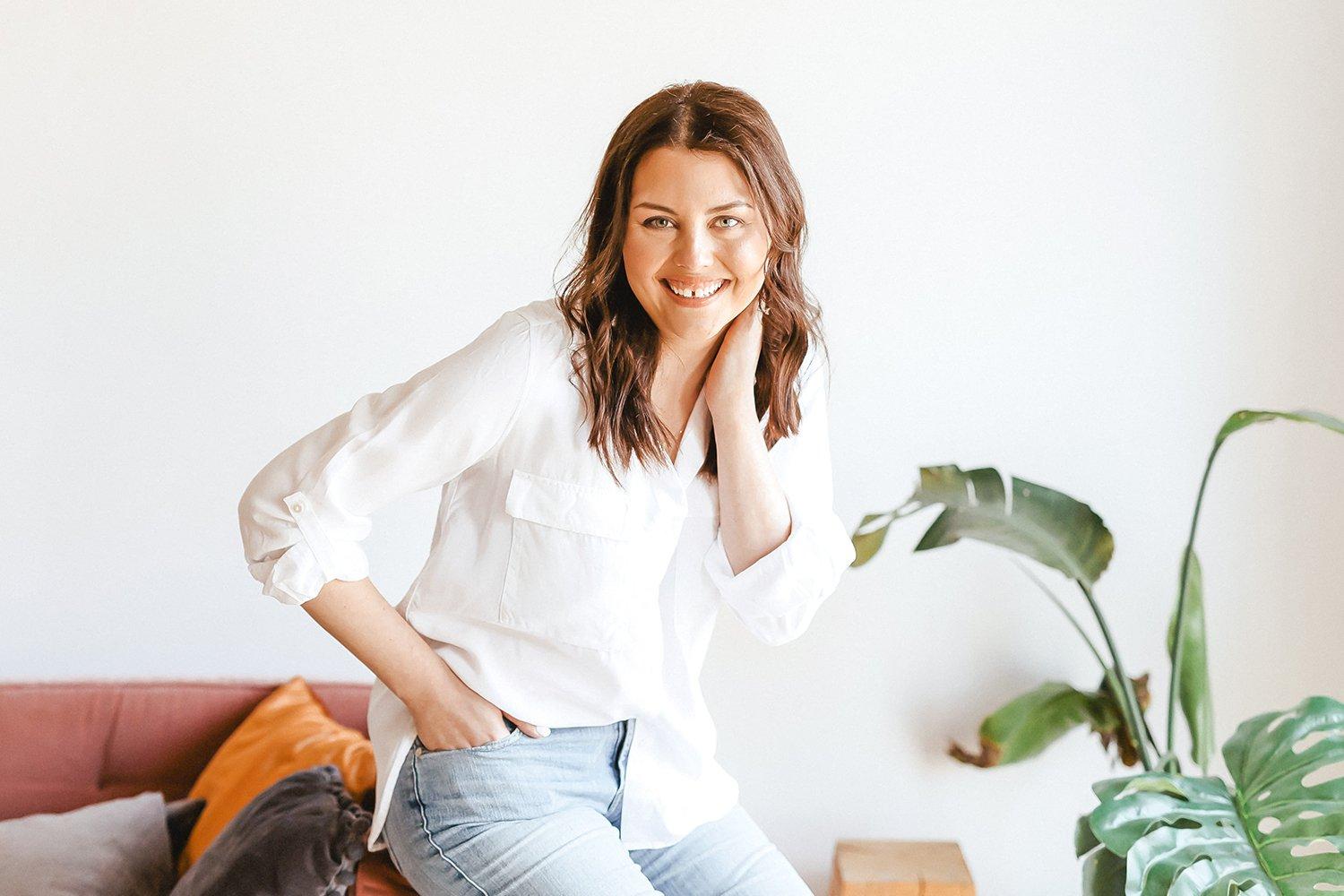 Sara Fortier, Outwitly's CEO and founder, sitting on the edge of a red couch against a white background