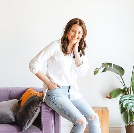 Sara Fortier, Outwitly's CEO and founder, sitting on the edge of a purple couch against a white background