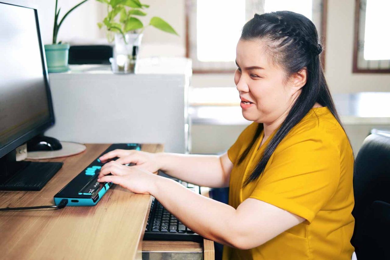 An image featuring a young girl confidently using assistive technology. The girl, who is blind, engages with the device, showcasing the empowering and inclusive nature of accessibility technology for individuals with visual impairments.
