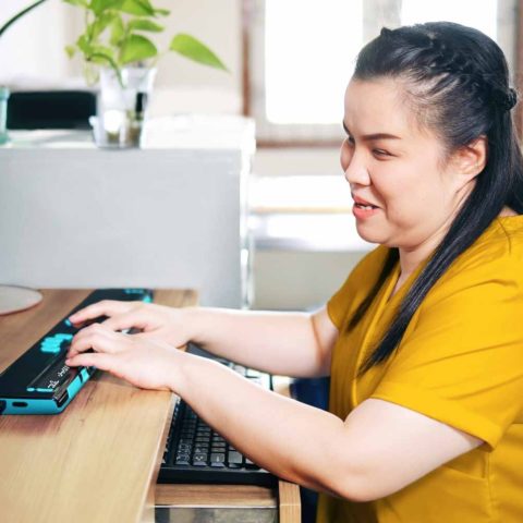An image featuring a young girl confidently using assistive technology. The girl, who is blind, engages with the device, showcasing the empowering and inclusive nature of accessibility technology for individuals with visual impairments.
