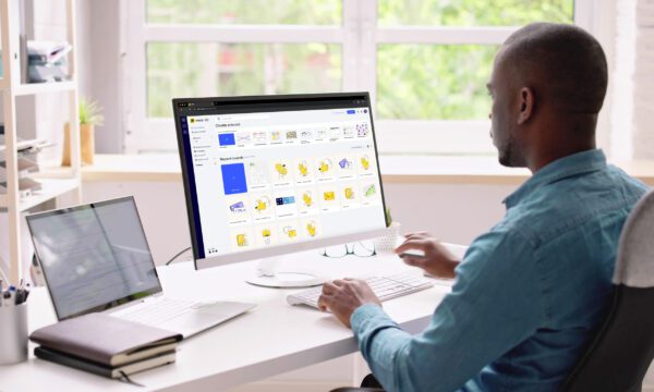 A photo of a professional man sitting at a work desk using the Miro software on his computer.