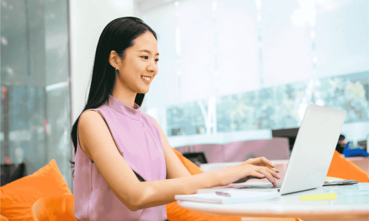 A woman smiling and building a great UX case study at her laptop