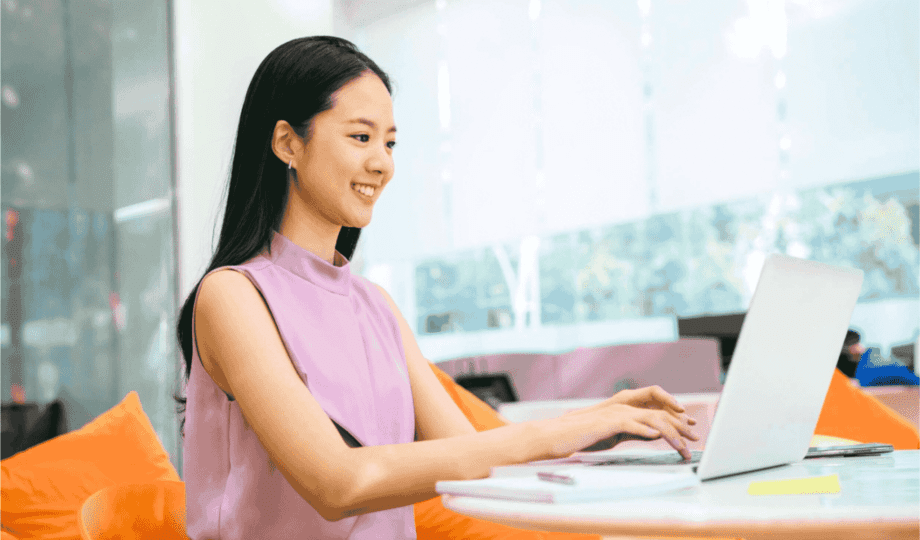 A woman smiling and building a great UX case study at her laptop