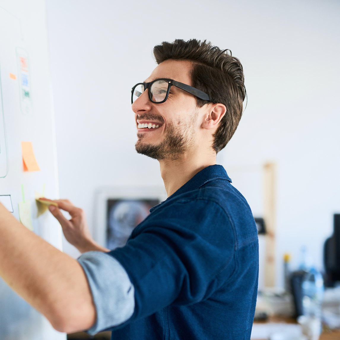 man smiling putting sticky notes on wall