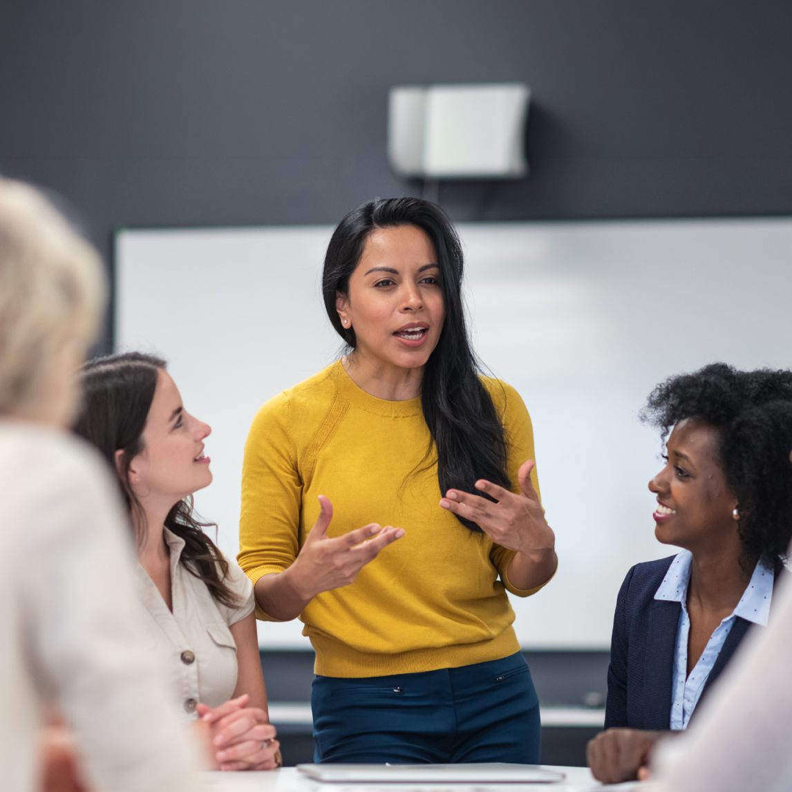A confident UX research expert leading an in-person workshop for a team to elevate shared practices.
